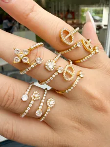Close-up of gold-tone rings with sparkling stones, floral and geometric designs on fingers
