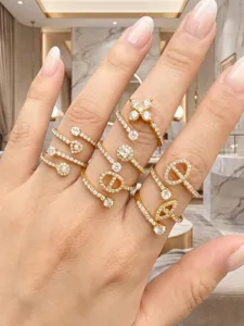 Close-up showing several gold-tone rings with clear zircon stones worn together on one hand