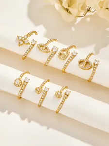 Eight gold-tone open rings with clear stones arranged on white display rods in two rows