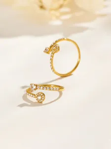 Two gold-tone rings with rows of clear stones and round cluster accents, arranged on a pale surface