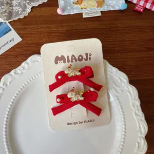 Ζευγάρι κόκκινα βελούδινα κλιπ με φιόγκους και λευκά σκυλάκια από σμάλτο, σε κάρτα προβολής