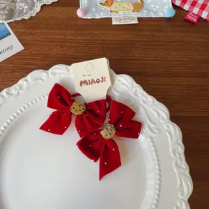 Δύο κόκκινοι βελούδινοι φιόγκοι με στρας και μικρά χρυσά διακοσμητικά σε σχήμα γάτας