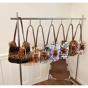 Flauschige Handtaschen mit Tiermustern, braunen Riemen und Teddyanhängern hängen am Metallständer