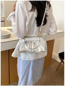 Vista da dietro di una modella con borsa argentata arricciata, dettagli dorati e tracolla