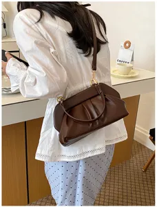 Borsa marrone in similpelle arricciata indossata a spalla, con fibbia dorata e tracolla regolabile