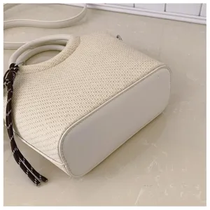 Gros plan sur le fond arrondi du sac tressé, avec panneau ivoire lisse et bordure cousue