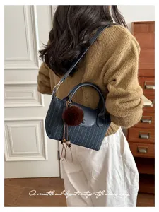 Vista posteriore di una donna con borsa blu a righe sottili, manici in similpelle e pompon decorativo