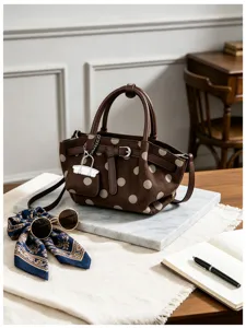Dettaglio di borsa marrone effetto camoscio a pois beige, con manici in pelle e fibbia