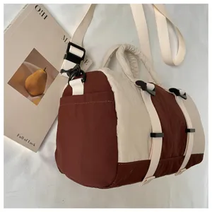 Dettaglio di una borsa bordeaux e crema con cinghie intrecciate regolabili e fibbie nere