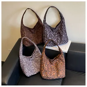 Quattro borse in tessuto leopardato, marrone, grigio, bianco e caramello, disposte su un divano nero