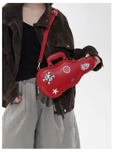 Borsa rossa a forma di chitarra indossata a tracolla, con ricami di teschio, smiley, stella e dadi
