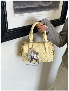 Borsa trapuntata giallo chiaro con borchie argentate e ciondolo a stella, tenuta in mano da una modella
