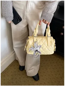 Primo piano di una borsa trapuntata giallo chiaro, con borchie argentate e ciondolo a stella
