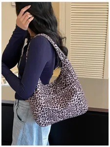 Vista laterale di una modella con una morbida borsa a spalla leopardata dalla forma a mezzaluna