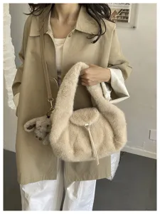 Woman carrying a beige fluffy handbag with a brown shoulder strap and a small plush charm