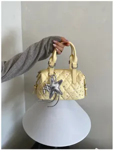 Borsa gialla trapuntata con strass argentati e ciondolo a stella, mostrata con i suoi doppi manici