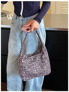 Vista indossata di una borsa morbida arricciata leopardata, portata a mano con jeans casual