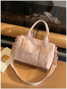 Close-up van een roze gekreukte stoffen tas met handvatten, rits en afneembare schouderband