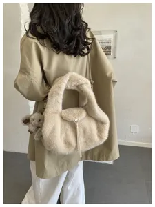 Back view of a woman carrying a cream plush bag with a teddy bear charm and long tassel
