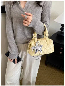 Modella con borsa trapuntata giallo chiaro, decorata con strass e un ciondolo a stella argentato