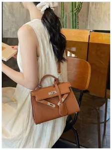 Una modella indossa una borsa marrone testurizzata con chiusura argentata e tracolla rimovibile