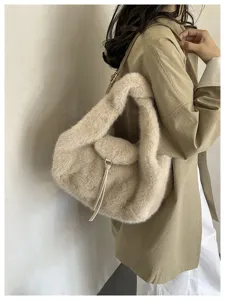 A beige faux-fur shoulder bag worn with a khaki coat, showing its soft crescent shape and strap.