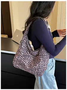 Vista laterale di una persona con una capiente borsa leopardata accanto a una scrivania e un laptop