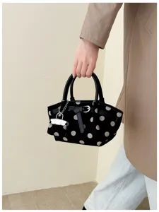 Borsa nera a pois bianchi portata a mano, con fondo arrotondato, doppi manici e catena argentata