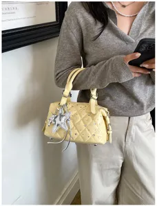 Borsa gialla trapuntata con strass e ciondolo a stella, portata da una persona in una scena