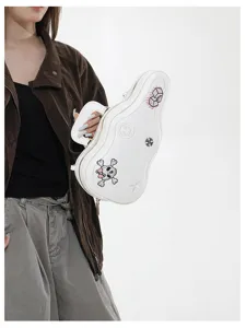 Una modella tiene una borsa bianca a forma di chitarra, con ricami di teschio, stella e fiori