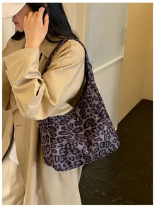 Una donna indossa un cappotto beige e porta al chiuso una borsa a spalla grigio-viola maculata