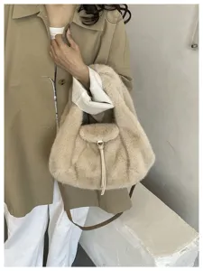Close-up of a beige faux-fur shoulder bag with a soft crescent shape and a long strap