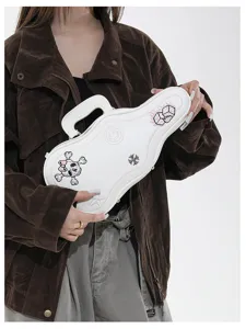 La modella tiene una borsa bianca a forma di chitarra, con ricami decorativi e manico