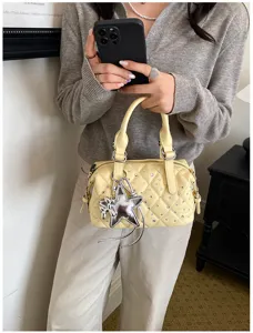 Borsa gialla trapuntata portata a mano, con borchie brillanti, ciondolo a stella argentato e catena.