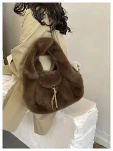 Close-up of a soft brown faux-fur bag with a beige leather tie and metal clasp, carried by a model
