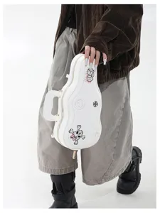 Vista di una borsa bianca a forma di chitarra, con toppe decorative e tenuta per il manico