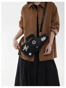 Sac noir en forme de guitare porté par un modèle, avec broderies, bandoulière réglable et poignée