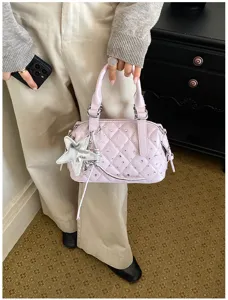 Una persona tiene una borsa trapuntata lilla chiaro, con strass e un ciondolo a stella argentato