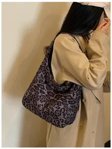 Scatto lifestyle di una modella con una capiente borsa a spalla leopardata nei toni viola e marrone