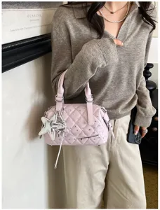 Una modella porta una borsa rosa trapuntata con strass, catena argentata e ciondolo a stella
