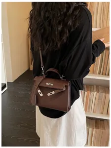 Vista posteriore di una modella con borsa marrone, chiusura metallica e tracolla removibile
