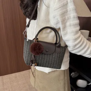 Borsa da donna a righe grigio scuro, con manici in pelle marrone e pompon, portata a tracolla