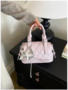 Dettaglio della trapuntatura rosa con strass, ciondolo a stella argentato e nappa decorativa.