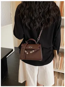Vista da dietro di una modella con borsa a tracolla marrone goffrata e dettagli metallici argentati