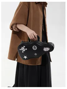 Una modella porta una borsa nera ondulata con toppe ricamate di teschio, smiley, stella e gemma