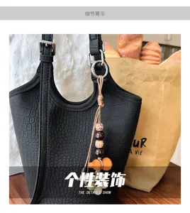 Bolso negro con relieve de cocodrilo, herrajes metálicos y colgante de cuentas de madera