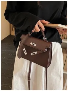 Una persona porta una borsa marrone testurizzata con fibbie metalliche e una lunga tracolla