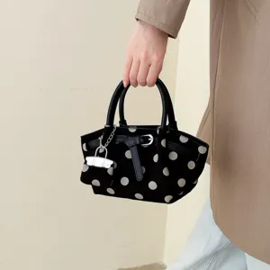 Borsa a secchiello nera a pois bianchi, portata dai manici con ciondolo e dettaglio a catena