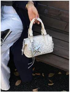 Borsa bianca trapuntata con strass e ciondolo a stella argentato, mostrata da una modella seduta