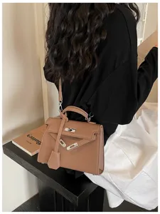 Vista laterale di una modella con borsa marrone effetto pelle martellata, manico e tracolla